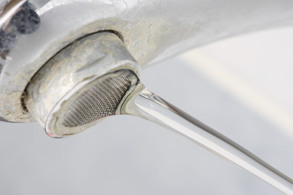 hard water stains visible on running bathroom sink faucet